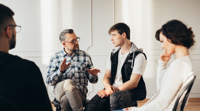 therapist talking with a young man in group therapy