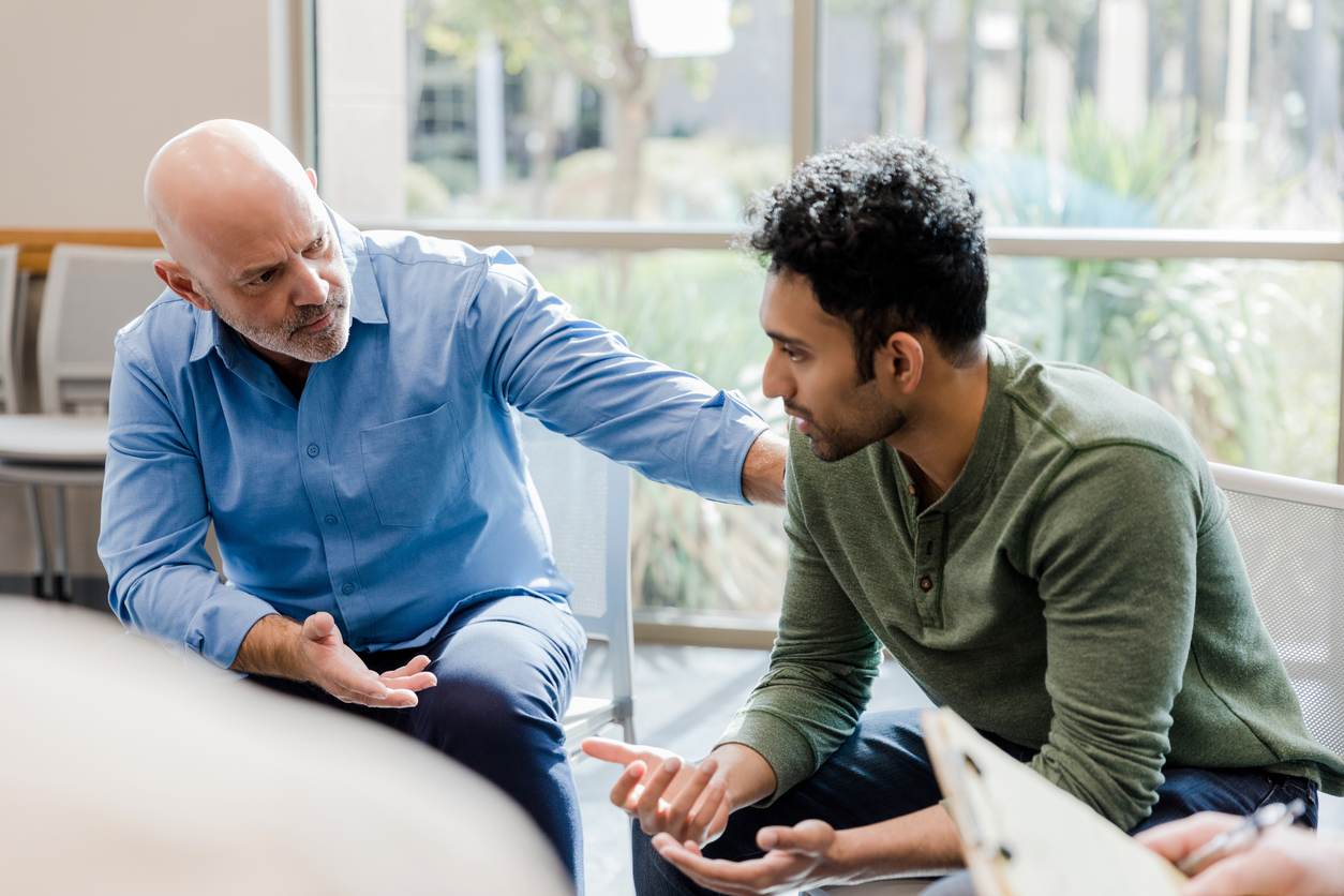 Mature man helps younger man verbalize problems in therapy photo