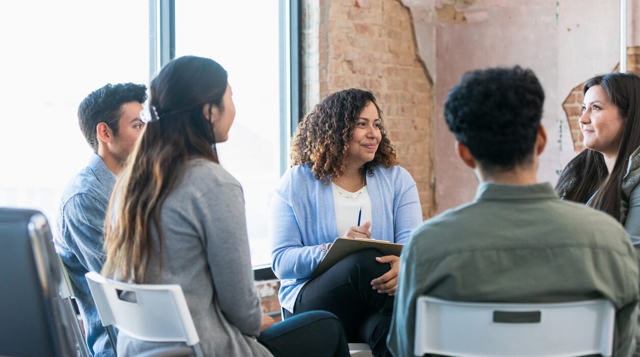 Therapy group listens attentively as young woman shares