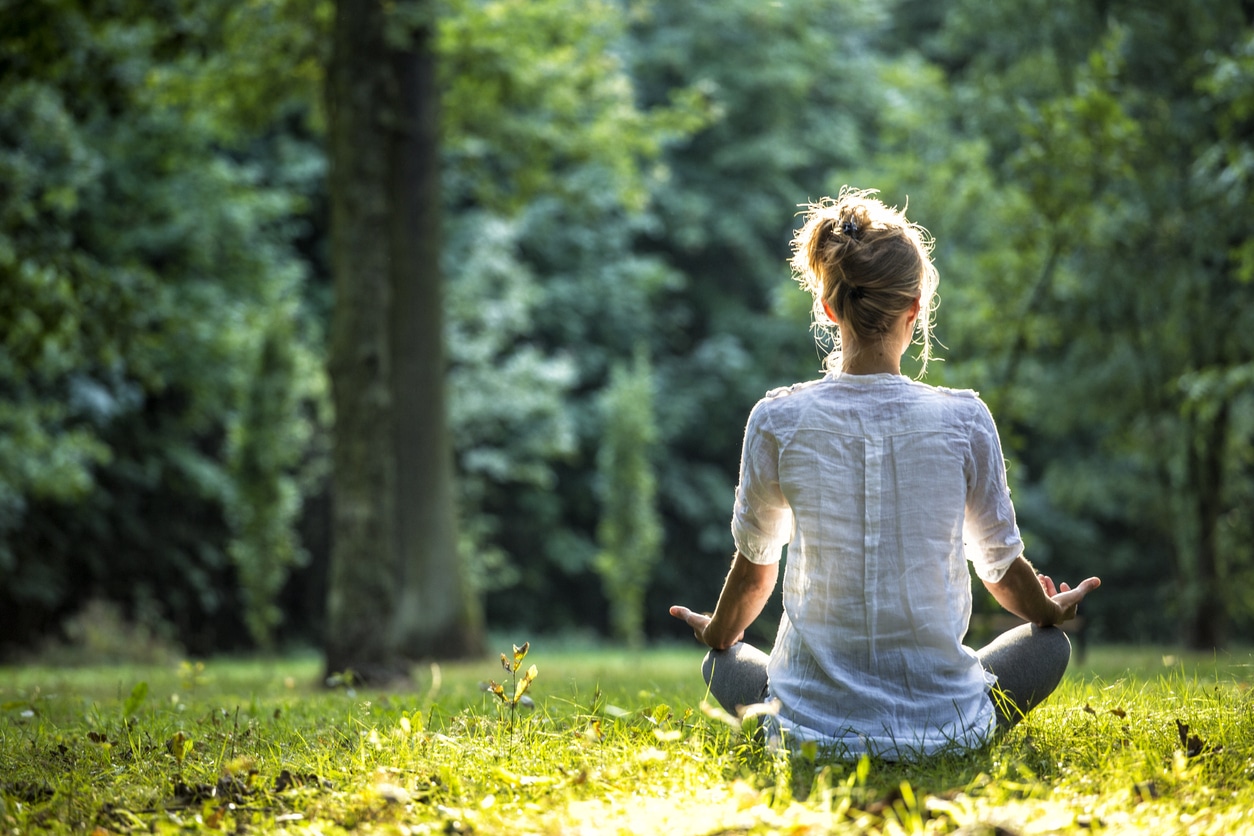 Young blonde woman meditating in the park